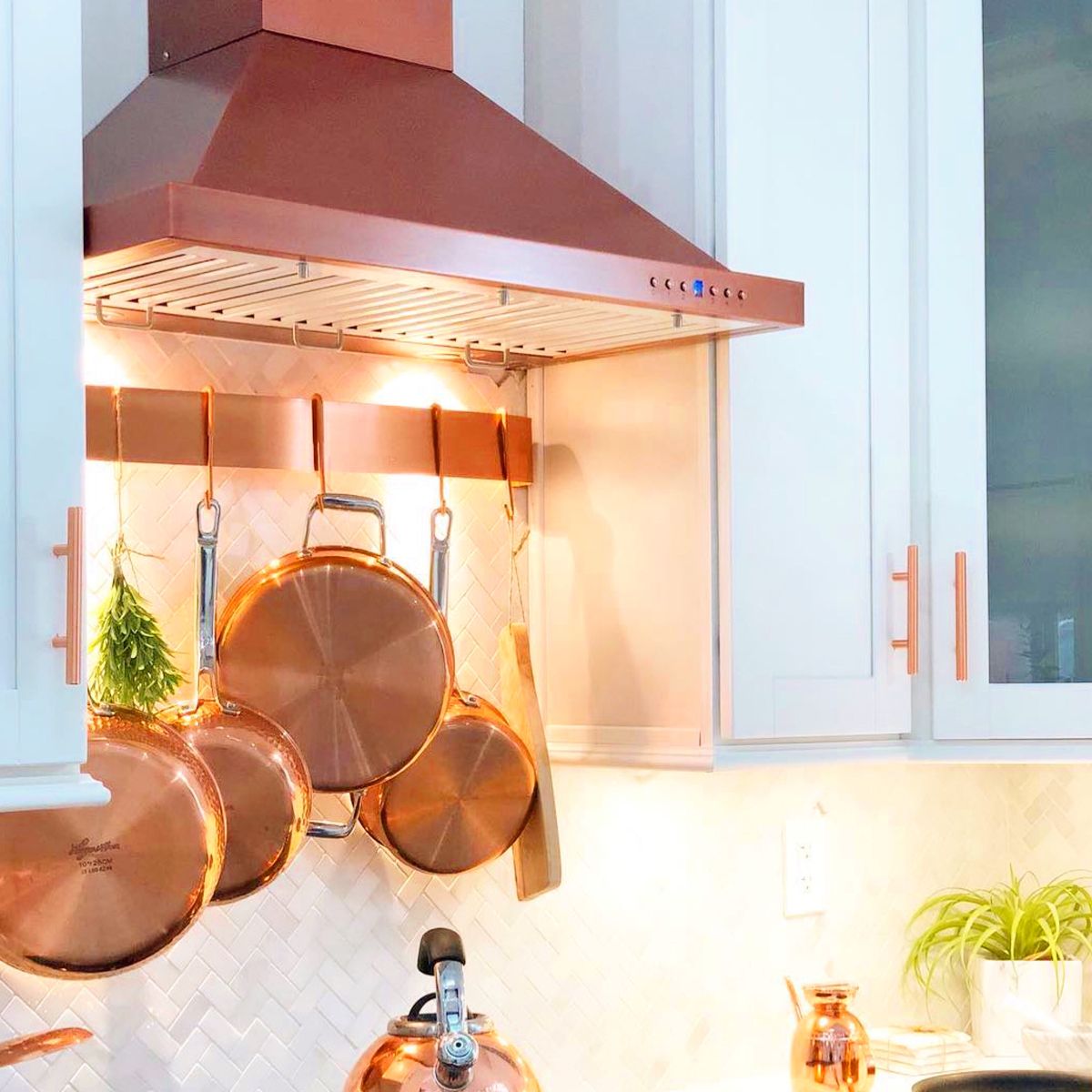 ZLINE Designer Series 7-Layer Copper Wall Mount Range Hood (8KBC) in a cottage kitchen with matching copper cookware.