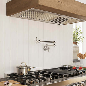 Farmhouse kitchen with gas range, a custom wooden hood using a ZLINE 46 in. Ducted Wall Mount Range Hood Insert in Outdoor Approved Stainless Steel (695-304-46), and a white tiled wall.
