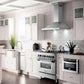 ZLINE Convertible Vent Wall Mount Range Hood in Stainless Steel with Crown Molding (KBCRN) in a farmhouse-style kitchen with Matching ZLINE Range and ZLINE Microwave