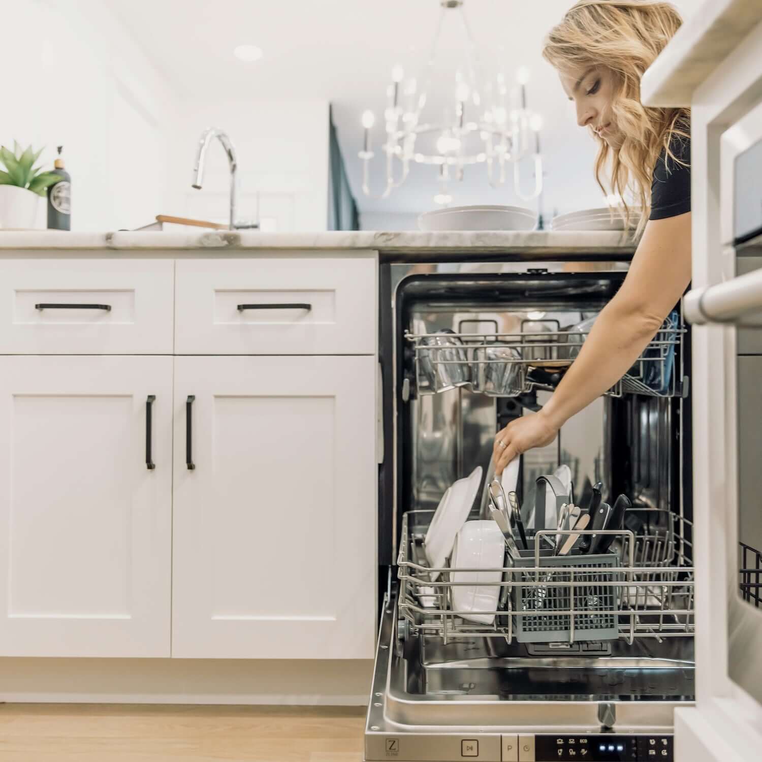 Woman loading a plate into a ZLINE dishwasher.