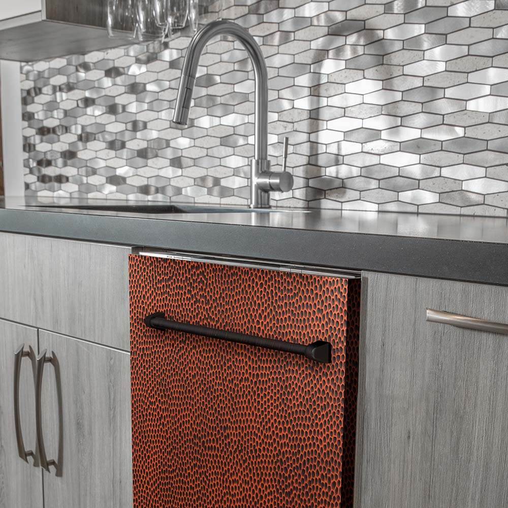 Hand-hammered copper dishwasher built-in to modern grey cabinets below a stainless steel faucet and speckled backsplash