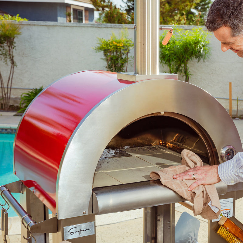 Person using Empava 25 in. Outdoor Wood Fired Pizza Oven in Stainless Steel with Red Accents (PG06) outdoors near a pool