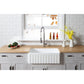 Farmhouse kitchen with Kingston Brass 30 in. Solid Surface White Stone Apron-Front Single Bowl Farmhouse Kitchen Sink with Strainer in Matte White (GKFA301810CD), wooden countertop, and gray cabinets.