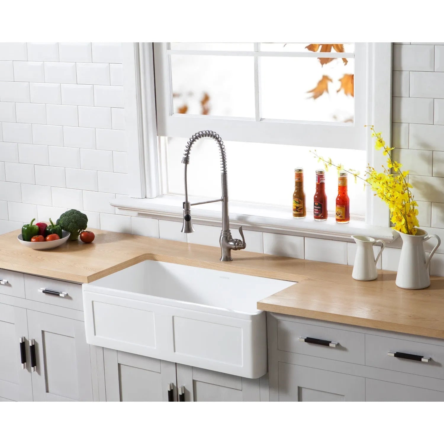 Farmhouse kitchen with a Kingston Brass 33 in. Solid Surface White Stone Apron-Front Single Bowl Farmhouse Kitchen Sink with Strainer in Matte White (GKFA331810DS), wooden countertop, and decorative elements.