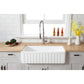 Farmhouse kitchen with Kingston Brass 36 in. Solid Surface Matte Stone Apron Front Farmhouse Single Bowl Kitchen Sink in Matte White (GKFA361810CD), wooden countertop, and decorative elements.