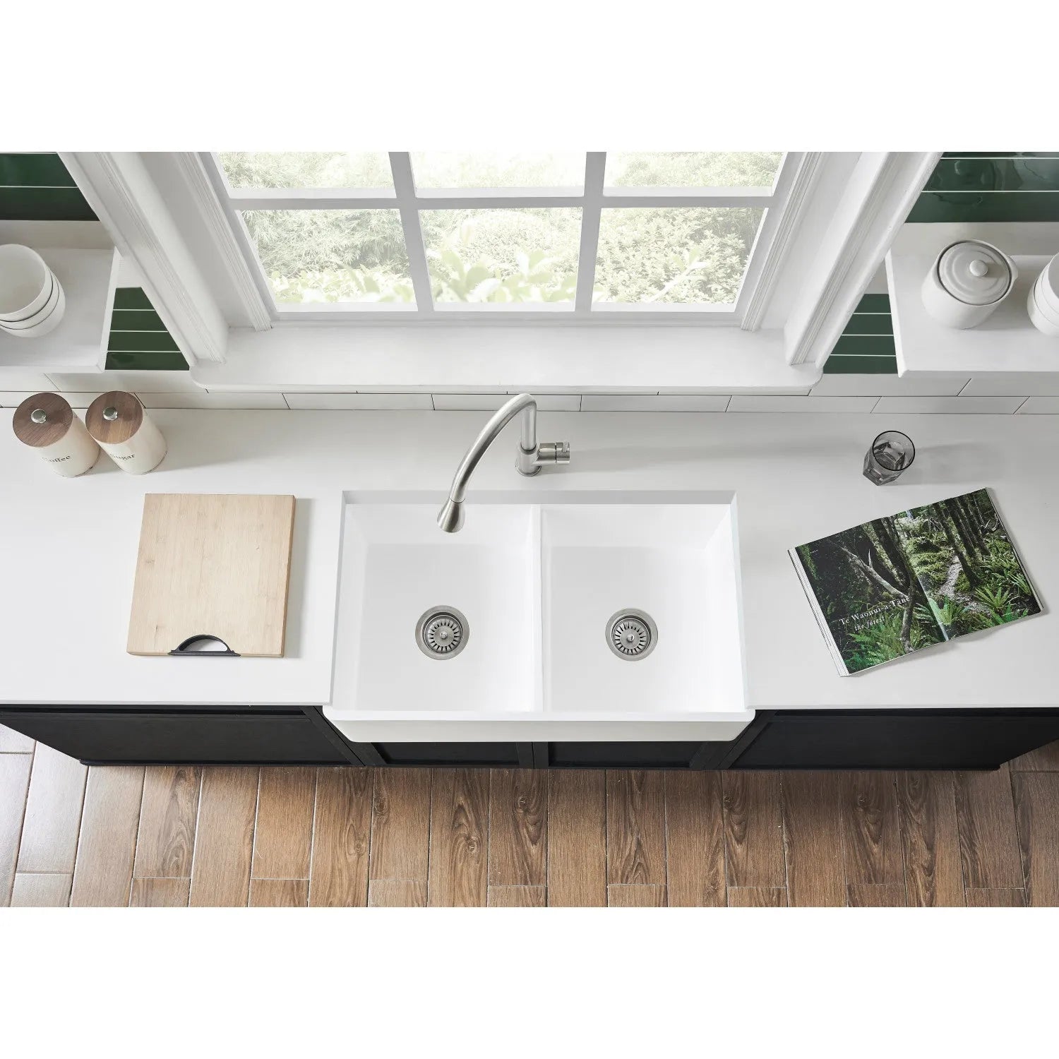 Kingston Brass Arcticstone 33 in. Solid Surface White Stone Apron-Front Double Bowl Farmhouse Kitchen Sink with Strainers in Matte/Glossy White (GPFA331810BCD) with a window above it in a modern kitchen setting.