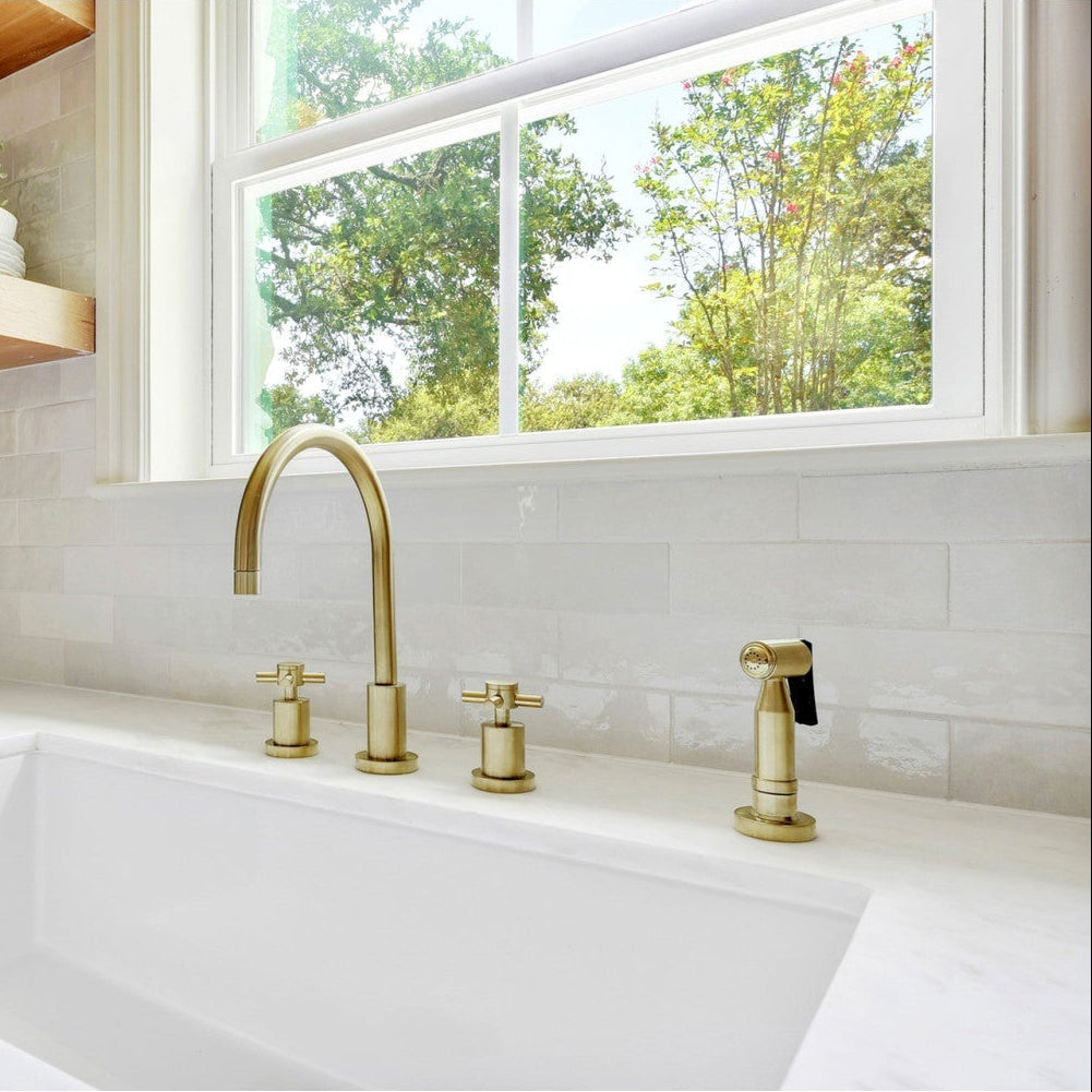 Kingston Brass Concord 8 in. Widespread Kitchen Faucet with Brass Sprayer (KS8726DXBS) in Brushed Brass on a kitchen sink with a window in the background