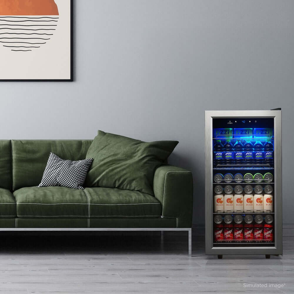 Modern living room with a green sofa and a TCL 18 in. 121 Can 2.4 Cu. Ft. Compact Freestanding Beverage Cooler with Glass Door (TRV121FAS) filled with drinks.