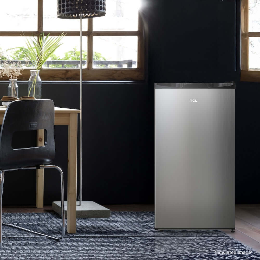 TCL 18 in. 3.1 Cu. Ft. Compact Single Door Mini Fridge in Silver (TRM31S4AV) in a modern room with a dining table and chairs.