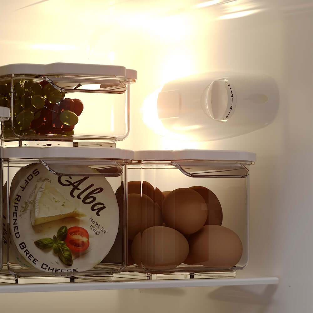 TCL 22 in. 7.3 Cu. Ft. Compact Top Freezer Refrigerator in White (TRT07T4AW) shelves with food storage containers holding grapes, cheese, and eggs.