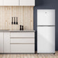 TCL 24 in. 10.1 Cu. Ft. Top Freezer Refrigerator in White (TRT10T4AW) in a modern kitchen with wooden wall and cabinets.