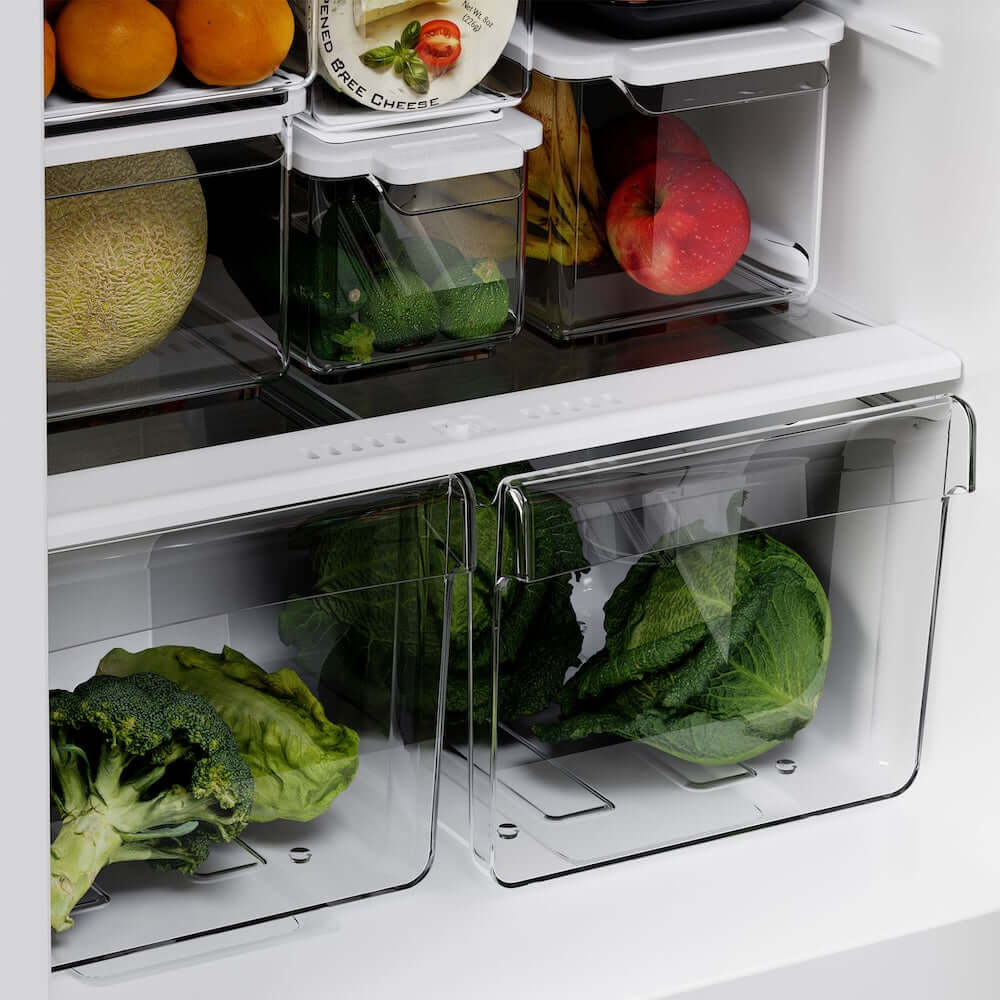 Open refrigerator with fresh produce including broccoli, lettuce, and oranges.