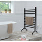 Bathroom with Kingston Brass Templeton Freestanding Plug-In Towel Warmer Matte Black, bathtub, and teddy bear on a wooden floor.