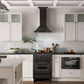 Modern farmhouse kitchen with black stove and ZLINE Convertible Vent Wall Mount Range Hood in Black Stainless Steel with Crown Molding (BSKBNCRN), white cabinets, and black countertops.