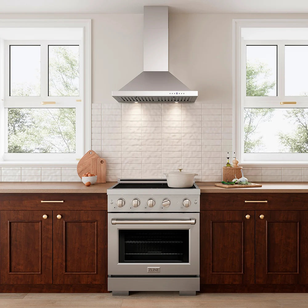 A stainless steel freestanding range with a matching range hood, set in a modern kitchen with dark wood cabinets, white subway tile backsplash, and windows.