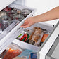 ZLINE Autograph Edition 36 in. 19.6 cu. ft. French Door Built-In Bottom Freezer Refrigerator with Water Dispenser and Ice Maker in Satin Stainless Steel with Polished Gold Accents (RBIVZ-SN-36-G) person accessing freezer drawer filled with various food items.