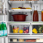 ZLINE Autograph Edition 36 in. 21.6 cu. ft 4-Door French Door Refrigerator with Water and Ice Dispenser in Stainless Steel with Polished Gold Modern Handles (RFMZ-W-36-FG) close-up front, food and drinks inside refrigeration compartment.