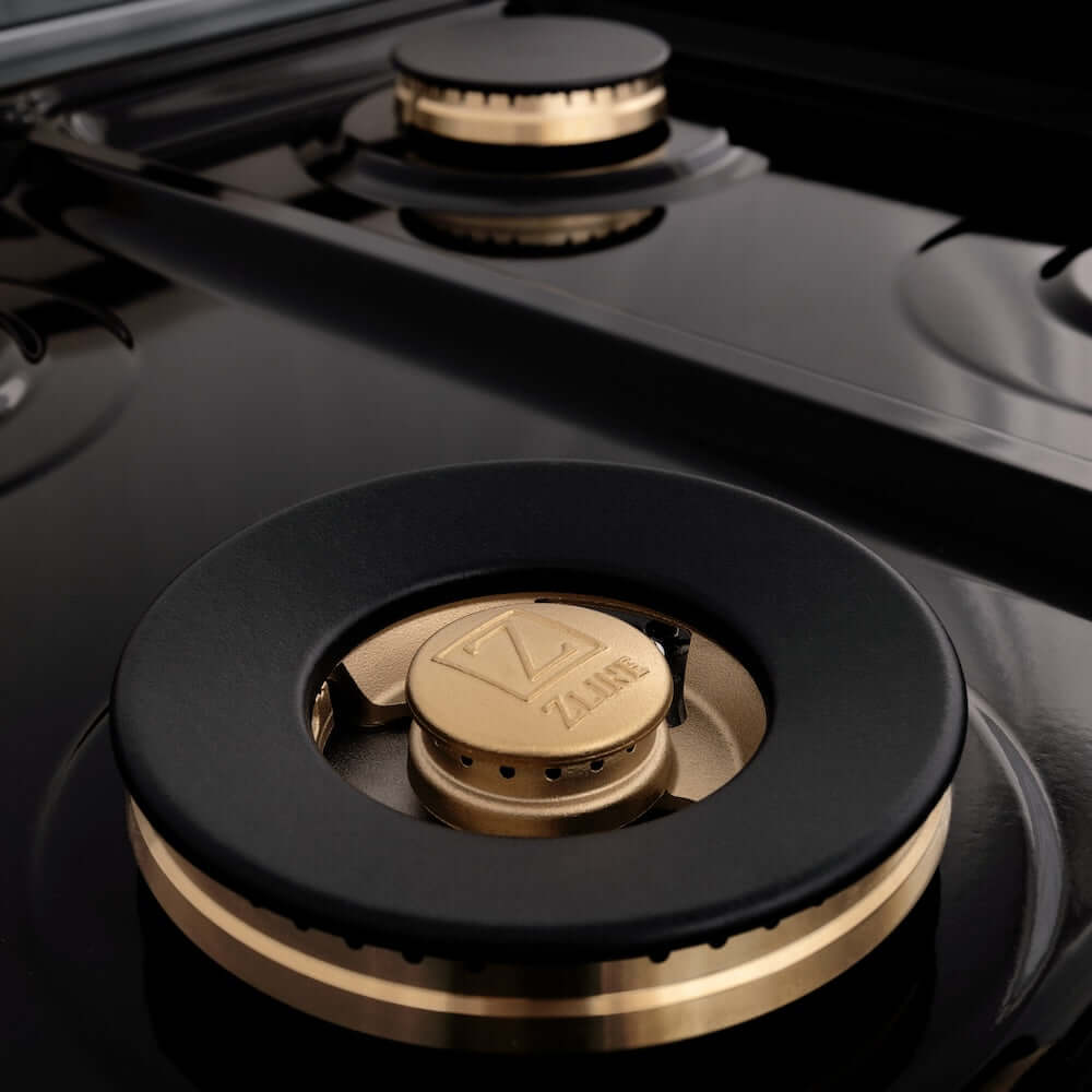 ZLINE Autograph Edition 36 in. 4.6 cu. ft. Dual Fuel Range with Gas Stove and Electric Oven in Fingerprint Resistant DuraSnow® Stainless Steel with Black Matte Door and Champagne Bronze Accents (RASZ-BLM-36-CB) brass burners close-up on cooktop without grates.