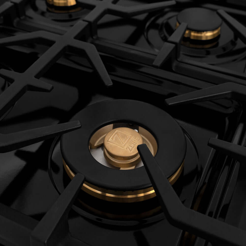 ZLINE Autograph Edition 60 in. 7.4 cu. ft. Legacy Dual Fuel Range with 9 Burner Gas Cooktop and 2 Electric Convection Ovens in Stainless Steel with White Matte Doors and Polished Gold Accents (RAZ-WM-60-G) close-up, large brass burner and cast-iron grates.