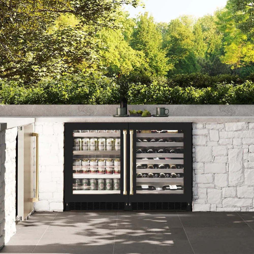 ZLINE Autograph Edition 24 in. Touchstone 151 Can Beverage Fridge With Black Matte Glass Door And Champagne Bronze Handle (RBSOZ-BLM-24-CB) front, in an outdoor patio area with a matching wine cooler against a stone wall and greenery.