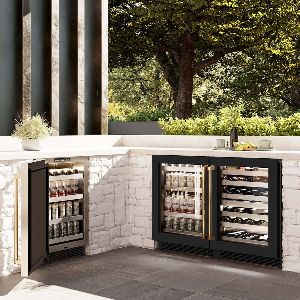 ZLINE Autograph Edition 24 in. Touchstone Dual Zone 44 Bottle Wine Cooler With Black Matte Glass Door And Polished Gold Handle (RWDOZ-BLM-24-G) side, in an outdoor patio area against a stone wall and greenery.