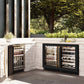 ZLINE Autograph Edition 24 in. Touchstone Dual Zone 44 Bottle Wine Cooler With Black Matte Glass Door And Polished Gold Handle (RWDOZ-BLM-24-G) side, in an outdoor patio area against a stone wall and greenery.
