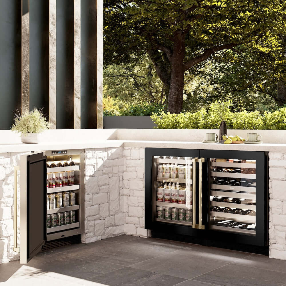 ZLINE Autograph Edition 24 in. Touchstone 151 Can Beverage Fridge With Black Stainless Steel Glass Door And Champagne Bronze Handle (RBSOZ-BS-24-CB) side, in an outdoor patio area against a stone wall and greenery.