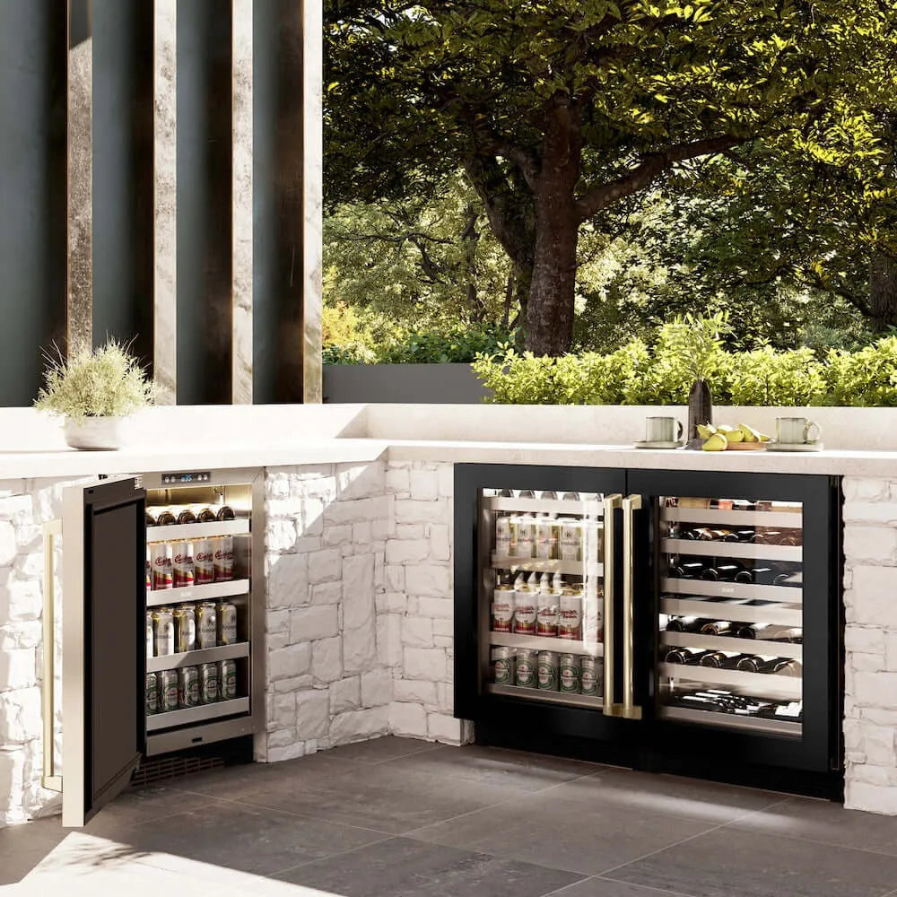 ZLINE Autograph Edition 24 in. Touchstone 151 Can Beverage Fridge With Black Stainless Steel Glass Door And Champagne Bronze Handle (RBSOZ-BS-24-CB) side, in an outdoor patio area against a stone wall and greenery.