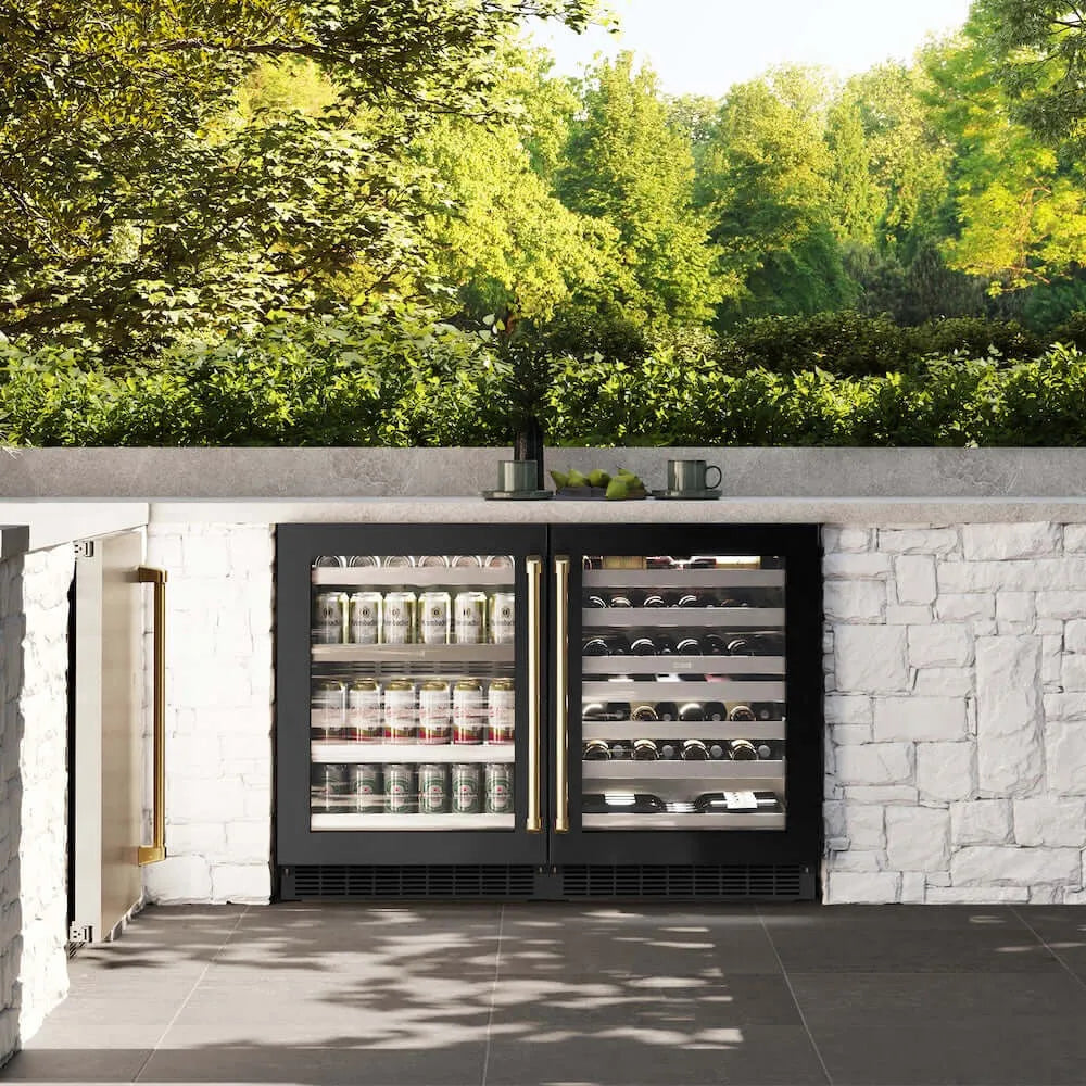 ZLINE Autograph Edition 24 in. Touchstone 151 Can Beverage Fridge With Black Stainless Steel Glass Door And Polished Gold Handle (RBSOZ-BS-24-G) front, in an outdoor patio area with a matching wine cooler against a stone wall and greenery.