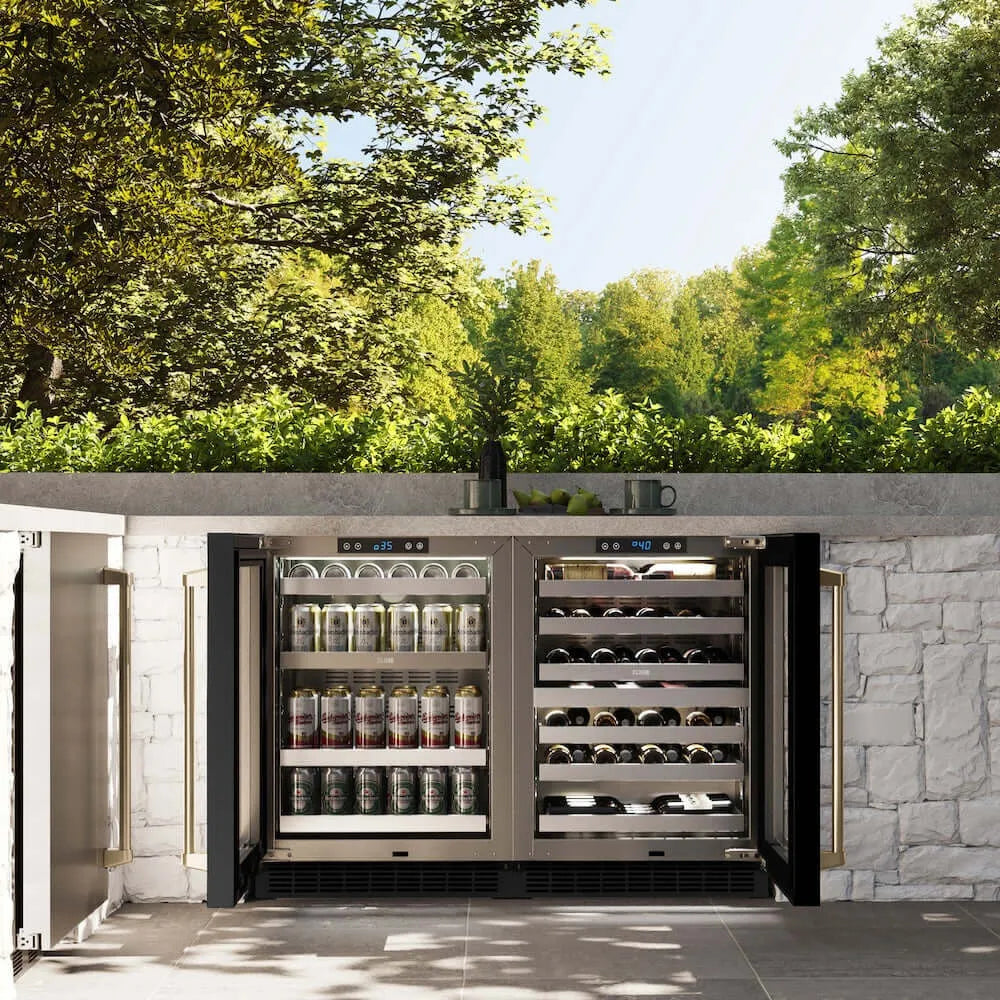 ZLINE Autograph Edition 24 in. Touchstone Dual Zone 44 Bottle Wine Cooler With Black Stainless Steel Glass Door And Champagne Bronze Handle (RWDOZ-BS-24-CB) front, open, in an outdoor patio area with a matching beverage fridge against a stone wall and greenery.