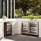 ZLINE Autograph Edition 24 in. Touchstone 151 Can Beverage Fridge With Satin Stainless Steel Glass Door And Champagne Bronze Handle (RBSOZ-SN-24-CB) side, in an outdoor patio area against a stone wall and greenery.