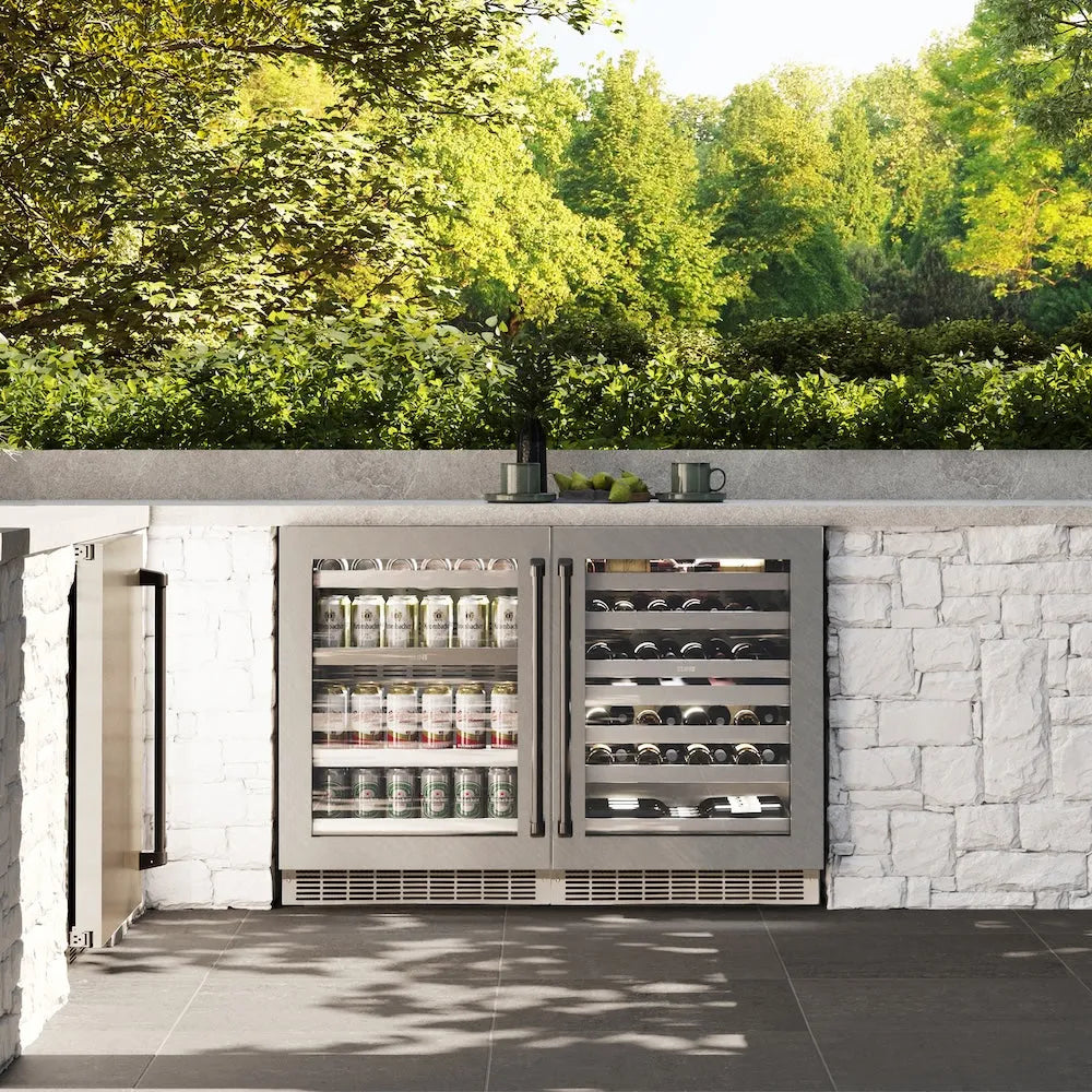 ZLINE Autograph Edition 24 in. Touchstone 151 Can Beverage Fridge With Satin Stainless Steel Glass Door And Matte Black Handle (RBSOZ-SN-24-MB) front, in an outdoor patio area with a matching wine cooler against a stone wall and greenery.