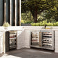 ZLINE Autograph Edition 24 in. Touchstone Dual Zone 44 Bottle Wine Cooler with Satin Stainless Steel Glass Door and Polished Gold Handle (RWDOZ-SN-24-G) side, in an outdoor patio area against a stone wall and greenery.
