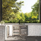 Outdoor kitchen with ZLINE Autograph Edition 24 in. Touchstone 151 Can Beverage Fridge with Stainless Steel Glass Door and Matte Black Handle (RBSOZ-GS-24-MB) and stone wall, surrounded by greenery
