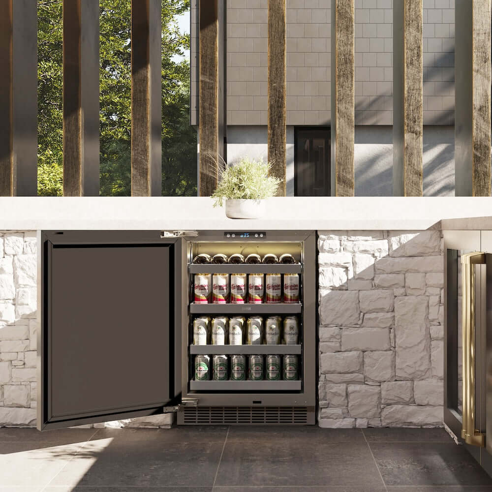ZLINE Autograph Edition 24 in. Touchstone 151 Can Beverage Fridge With Solid Stainless Steel Door And Champagne Bronze Handle (RBSOZ-ST-24-CB) front, open, in an outdoor patio area with a matching wine cooler against a stone wall and greenery.