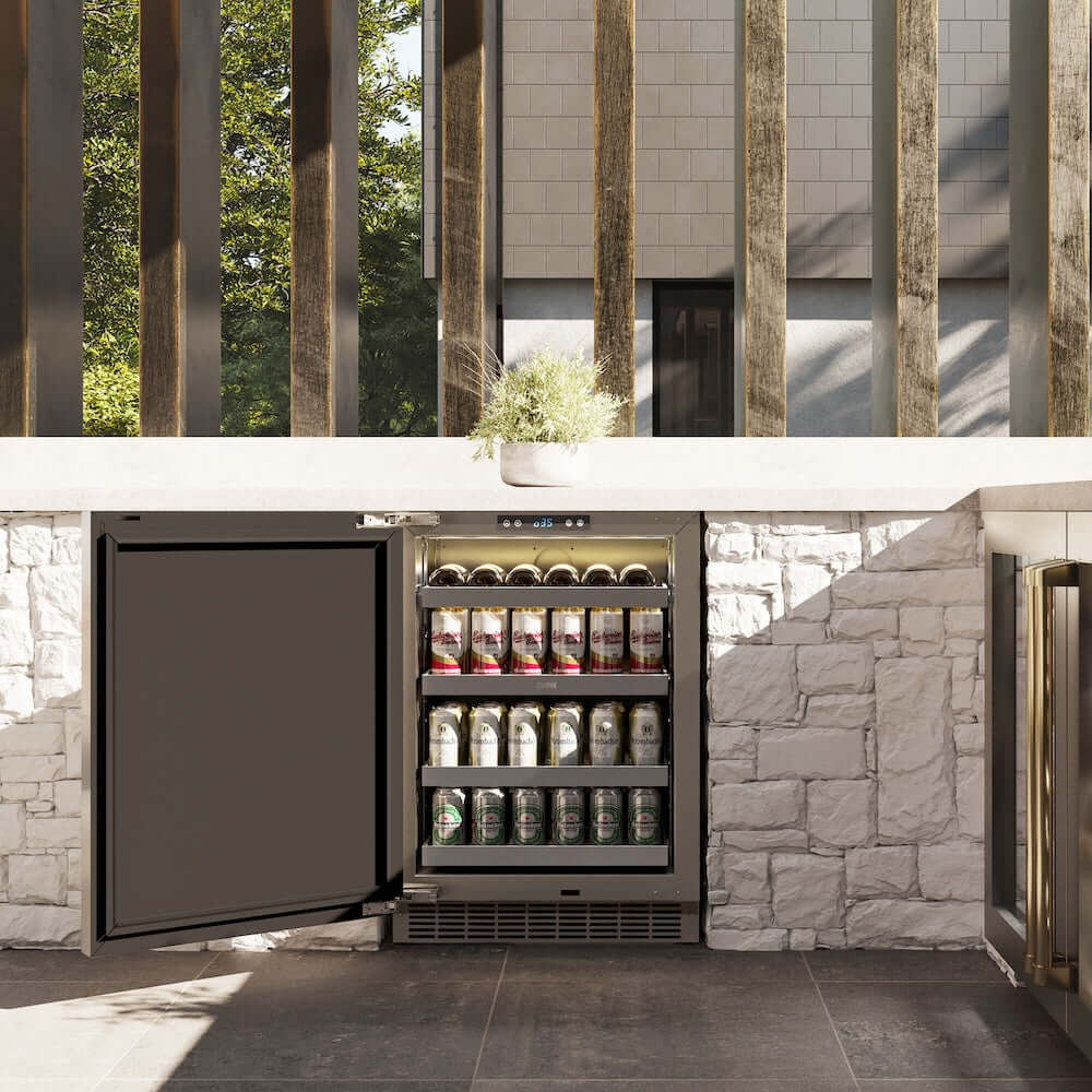 ZLINE Autograph Edition 24 in. Touchstone 151 Can Beverage Fridge With Solid Stainless Steel Door And Polished Gold Handle (RBSOZ-ST-24-G) front, open, in an outdoor patio area with a matching wine cooler against a stone wall and greenery.