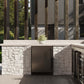 ZLINE Autograph Edition 24 in. Touchstone 151 Can Beverage Fridge With Solid Stainless Steel Door And Matte Black Handle (RBSOZ-ST-24-MB) front, in an outdoor patio area with a matching wine cooler against a stone wall and greenery.
