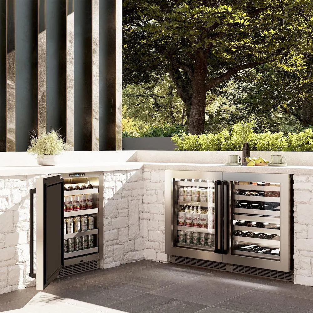 Outdoor kitchen with ZLINE Autograph Edition 24 in. Touchstone Dual Zone 44 Bottle Wine Cooler with Stainless Steel Glass Door and Matte Black Handle (RWDOZ-GS-24-MB) against a stone wall and greenery.