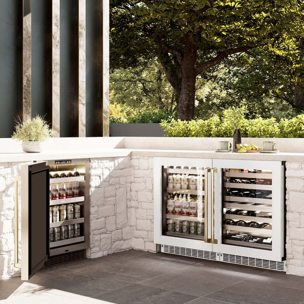 ZLINE Autograph Edition 24 in. Touchstone 151 Can Beverage Fridge With White Matte Glass Door And Champagne Bronze Handle (RBSOZ-WM-24-CB) side, in an outdoor patio area against a stone wall and greenery.