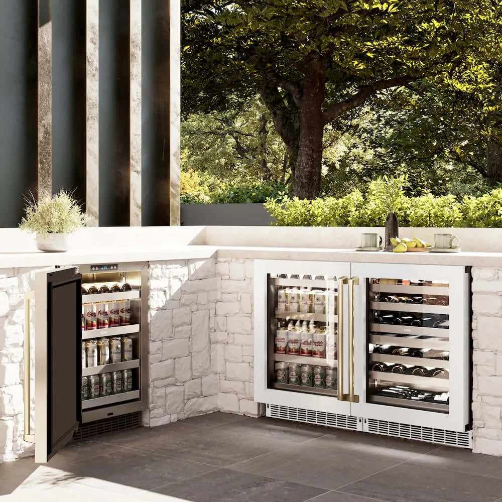 ZLINE Autograph Edition 24 in. Touchstone 151 Can Beverage Fridge With White Matte Glass Door And Champagne Bronze Handle (RBSOZ-WM-24-CB) side, in an outdoor patio area against a stone wall and greenery.
