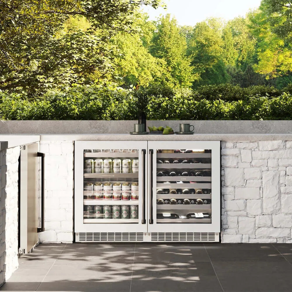 ZLINE Autograph Edition 24 in. Touchstone 151 Can Beverage Fridge With White Matte Glass Door And Matte Black Handle (RBSOZ-WM-24-MB) front, in an outdoor patio area with a matching wine cooler against a stone wall and greenery.