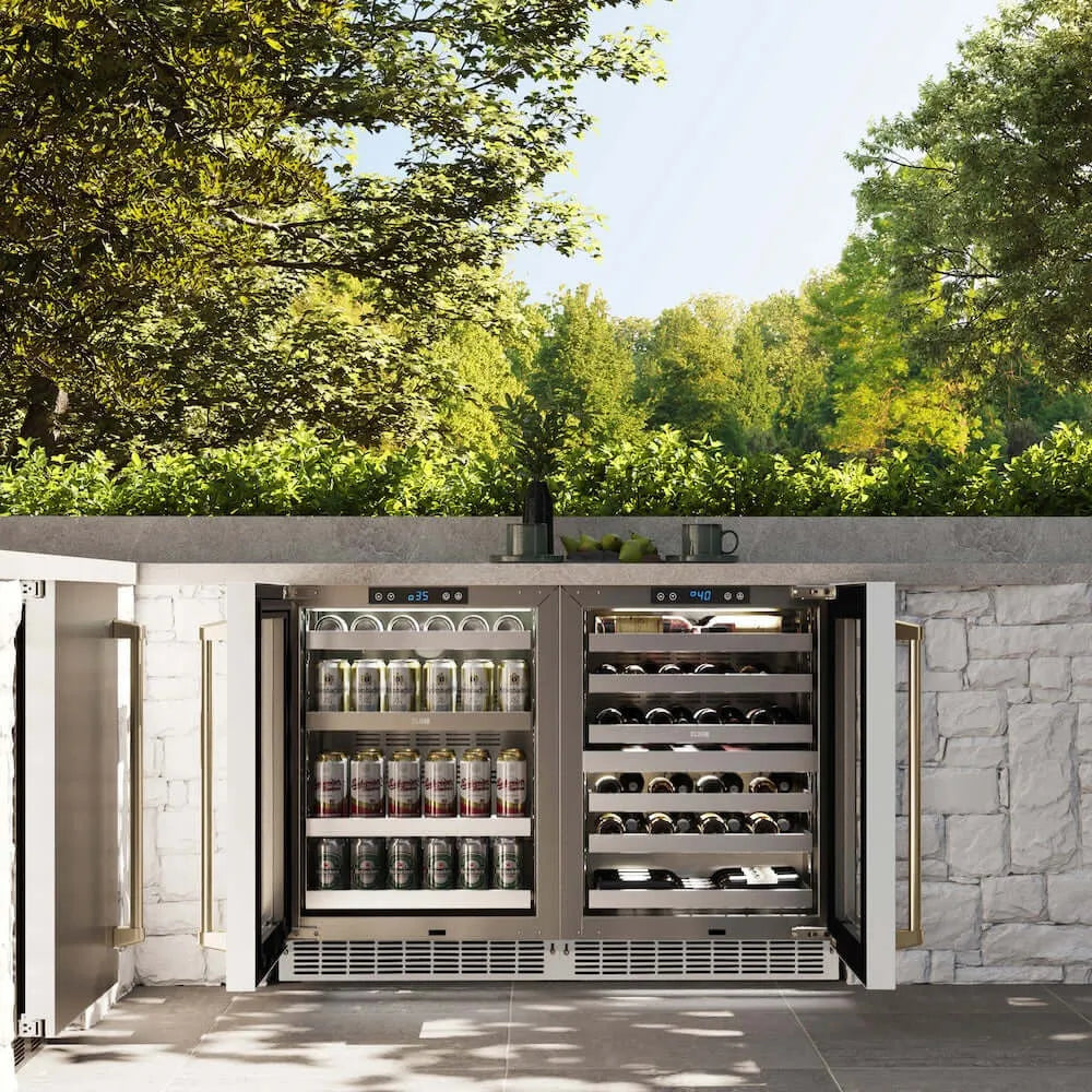 ZLINE Autograph Edition 24 in. Touchstone Dual Zone 44 Bottle Wine Cooler With White Matte Glass Door And Champagne Bronze Handle (RWDOZ-WM-24-CB) front, open, in an outdoor patio area with a matching beverage fridge against a stone wall and greenery.