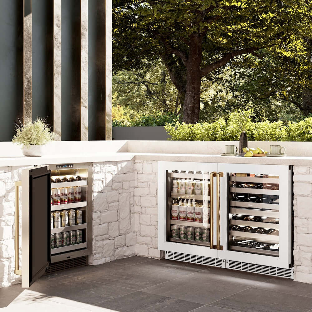 ZLINE Autograph Edition 24 in. Touchstone Dual Zone 44 Bottle Wine Cooler With White Matte Glass Door And Polished Gold Handle (RWDOZ-WM-24-G) side, in an outdoor patio area against a stone wall and greenery.