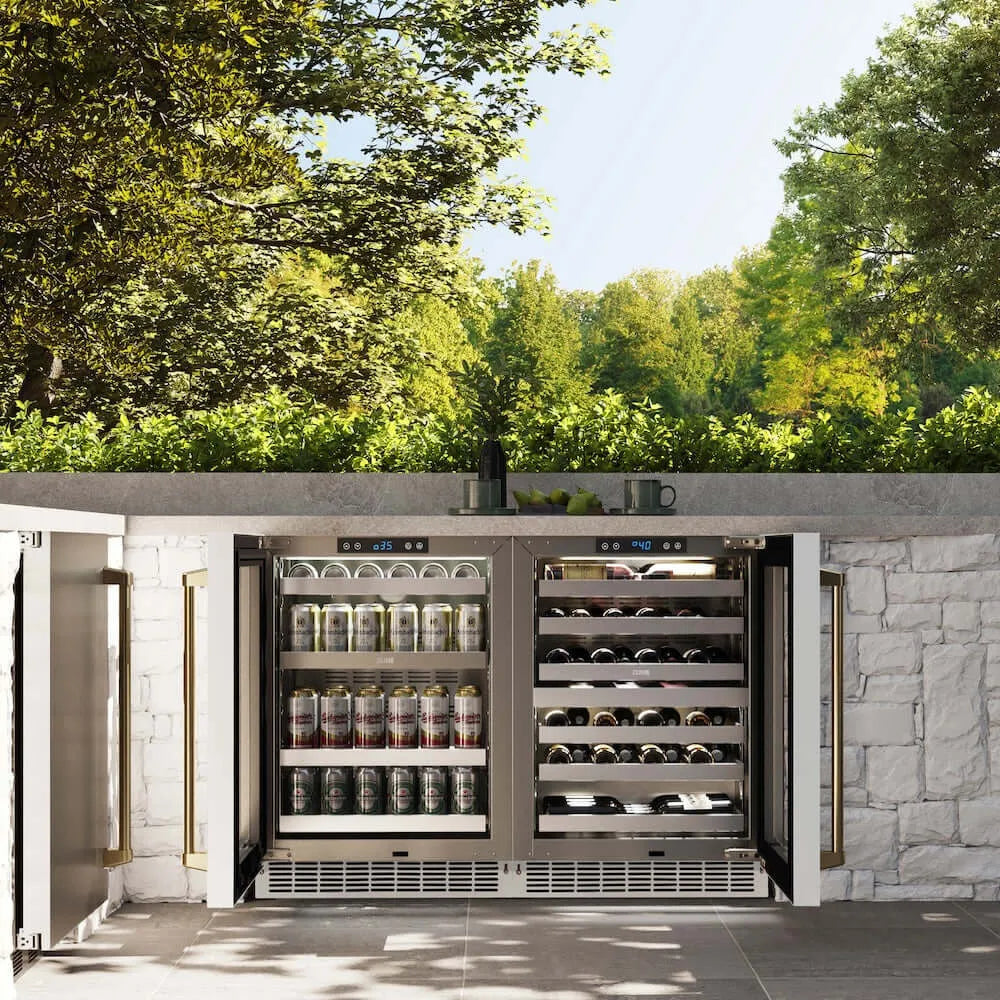 ZLINE Autograph Edition 24 in. Touchstone Dual Zone 44 Bottle Wine Cooler With White Matte Glass Door And Polished Gold Handle (RWDOZ-WM-24-G) front, open, in an outdoor patio area with a matching beverage fridge against a stone wall and greenery.