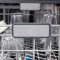 ZLINE Autograph Edition 24 in. Monument Series 3rd Rack Top Touch Control Tall Tub Dishwasher in Stainless Steel with Polished Gold Helix Handle, 45dBa (DWMTZ-30424-KG) logo on dish rack with dishes in the background.