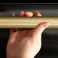 ZLINE Autograph Edition 24 in. Monument Series 3rd Rack Dishwasher with Auto Door Open Drying, 44dBa, Black Stainless Steel Panel with Champagne Bronze Helix Handle (DWMTZ-BS-24-KCB), close-up, person holding Helix handle showing knurled diamond texture.