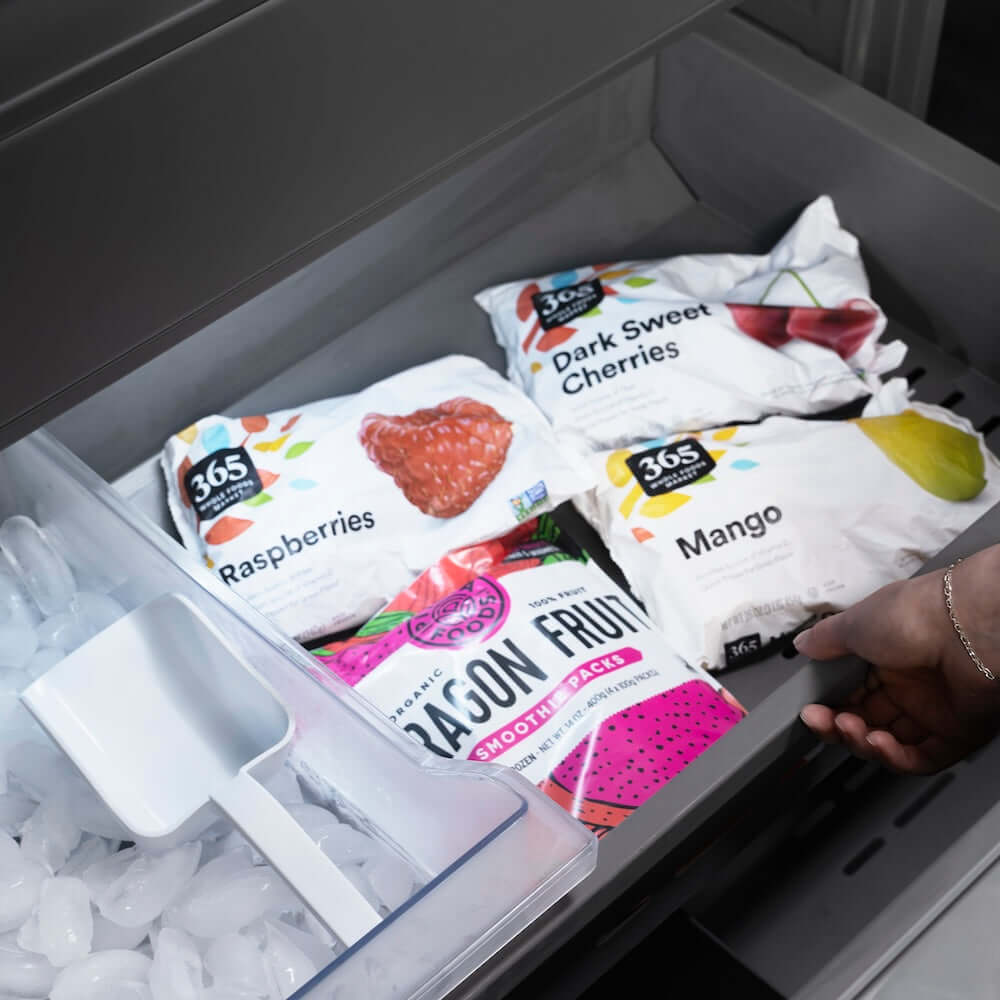 ZLINE Autograph Edition 30 in. 16.1 cu. ft. Built-In Bottom Freezer Refrigerator with Water Dispenser and Ice Maker in Black Stainless Steel with Graphite Gray Interior and Polished Gold Helix Handles (GRBIVZ-BS30KG) frozen food packages including raspberries, dark sweet cherries, and mangoes in bottom freezer drawer.