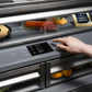 ZLINE Autograph Edition 36 in. 19.6 cu. ft. French Door Built-In Bottom Freezer Refrigerator with Water Dispenser and Ice Maker in Black Stainless Steel with Graphite Gray Interior and Polished Gold Helix Handles (GRBIVZ-BS36KG) hand adjusting digital temperature control inside refrigeration compartment with food items inside.