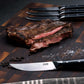 ZLINE 6-Piece Professional German Steel Steak Knife Set (STK-GS-6) on a cutting board with steak.
