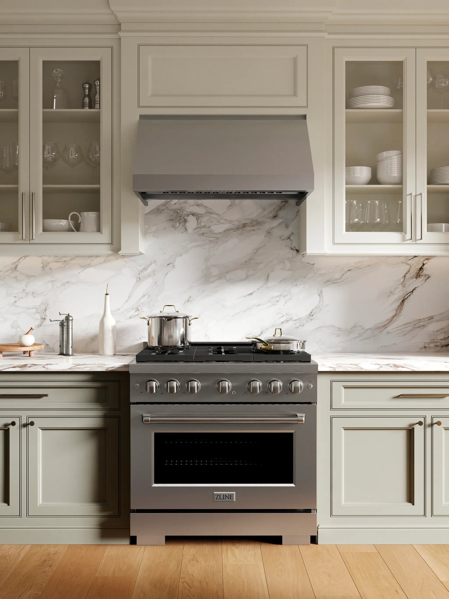 Luxury kitchen with stainless steel range and range hood and marble backsplash
